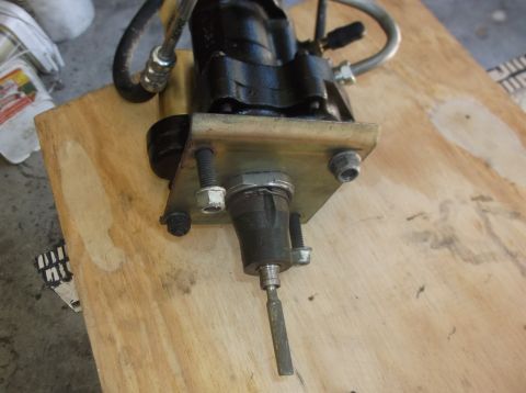 1979 Ford Ranchero - A close-up, high-angle shot shows a black clutch master cylinder assembly mounted on a piece of plywood. The assembly features a metal moun…