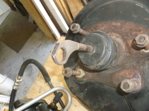 1979 Ford Ranchero - A close-up view of a brake booster assembly, likely from a 1979 Ford Ranchero, showing a metal bracket with a circular opening attached to…