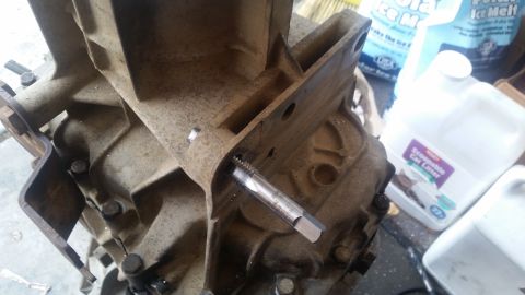 1985 Ford Bronco - A tap is being used to thread a hole in a dirty, cast-iron automotive transmission housing. In the background, containers of ice melt and c…