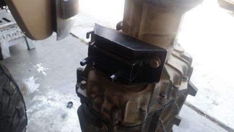 1985 Ford Bronco - A black transmission mount bracket is bolted to the side of a transmission housing. The bracket has two threaded studs protruding from its…