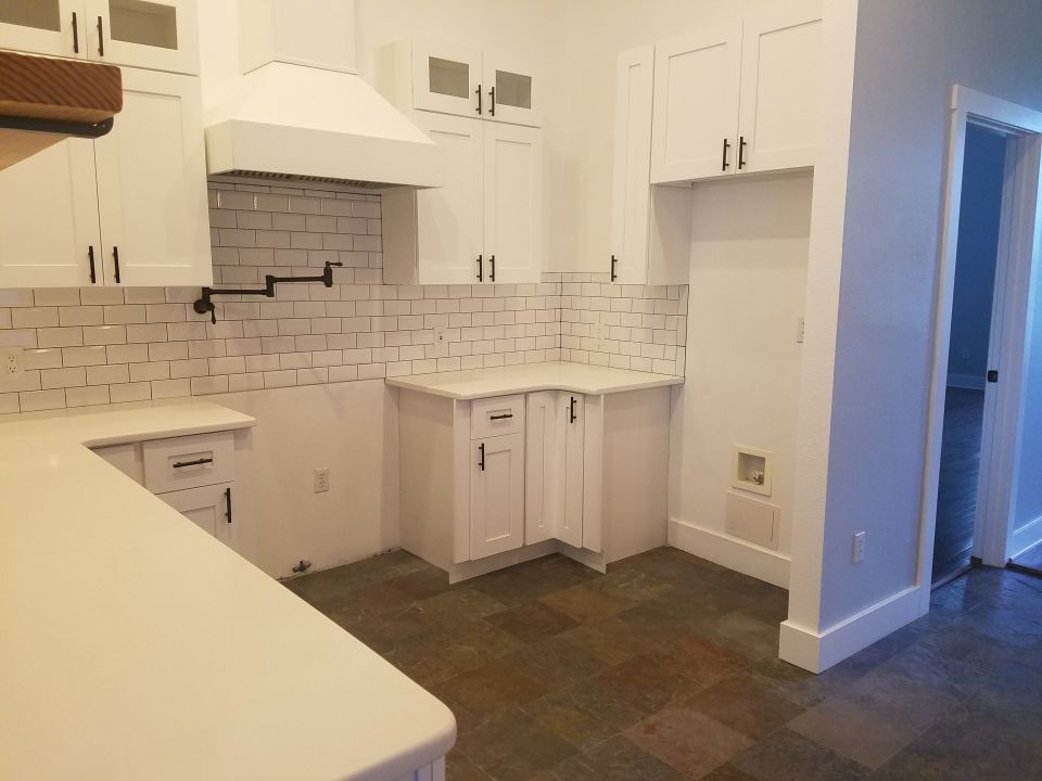 Photo of a white kitchen with subway tile backsplash and shaker cabinets