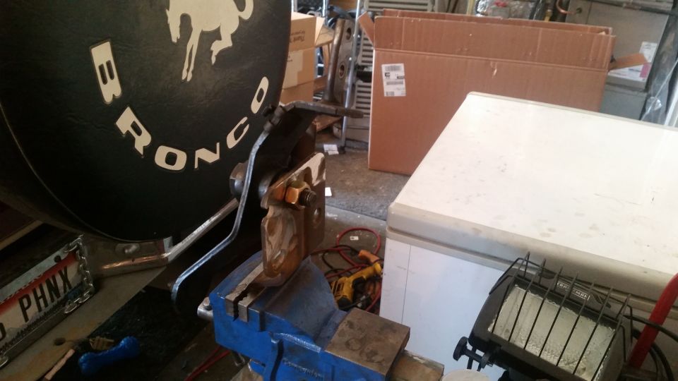 Close-up of "BRONCO" lettering on a black circular object in a vise.