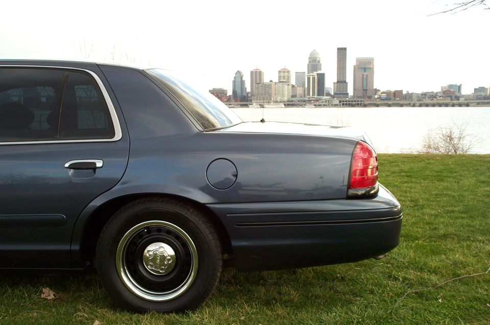 Rear quarter close-up of dark blue Crown Victoria with black steel wheel and chrome trim ring