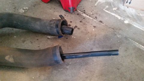 1985 Ford Bronco - Two large black rubber hoses are laid out on a concrete floor. One hose has a black plastic insert extending from its end, and the other ho…