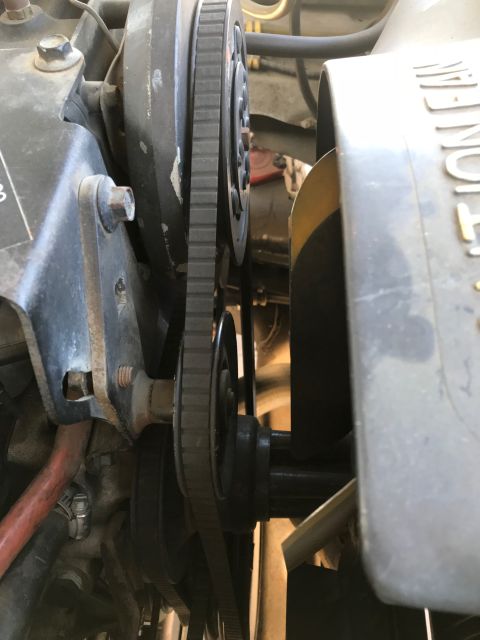 1979 Ford Bronco - A close-up view of the engine's V-belt system, showing multiple pulleys and the ribbed belts connecting them. A portion of the fan shroud i…