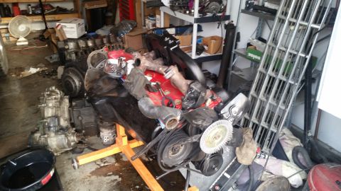 1985 Ford Bronco - A disassembled engine and transmission are laid out on the floor of a garage, with various tools and parts scattered around. The engine is…