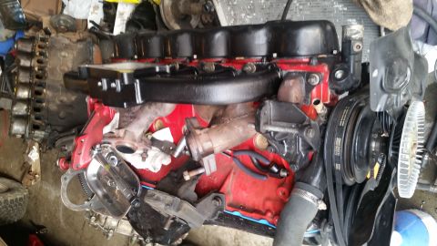 1985 Ford Bronco - A V8 engine is shown, possibly for an engine swap, with various components attached and some tools nearby.