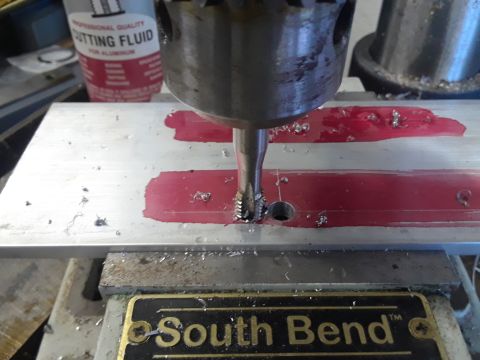 1985 Ford Bronco - A drill is used to tap threads into a metal plate, with cutting fluid present.