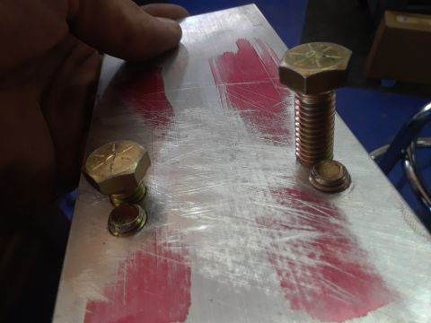 1985 Ford Bronco - A metal plate with red markings and bolts is shown up close, suggesting a mechanical part.