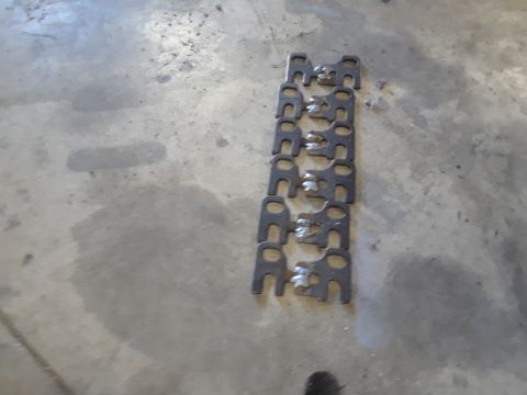 1985 Ford Bronco - Several metal brackets are arranged in a line on a concrete surface.