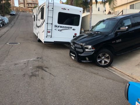 1992 Jeep Wrangler - A black Ram 1500 is seen towing a white Sunseeker RV down a residential street.