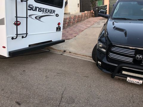 1992 Jeep Wrangler - A black pickup truck is parked next to a white Sunseeker RV in a driveway.