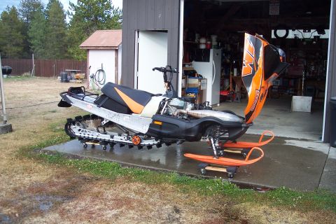 2004 Arctic Cat King Cat 900 - Snowmobile with hood open, parked outside a garage.