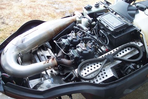 2004 Arctic Cat King Cat 900 - Close-up view of a snowmobile's engine compartment, showing the dual carburetors and exhaust system.