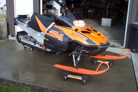 2004 Arctic Cat King Cat 900 - An Arctic Cat snowmobile is parked in front of a garage, resting on dollies.