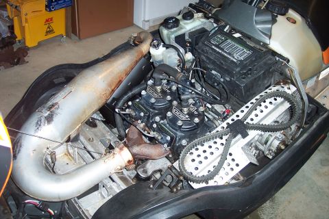 2004 Arctic Cat King Cat 900 - The engine compartment of a snowmobile, showing the engine, exhaust, and drive belt.