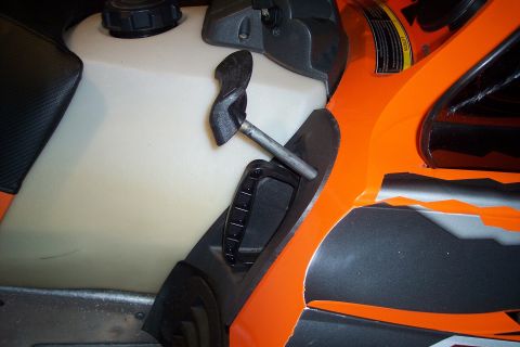 2004 Arctic Cat King Cat 900 - Close-up view of an orange snowmobile's fuel tank and a black handle, with a watermark at the bottom.