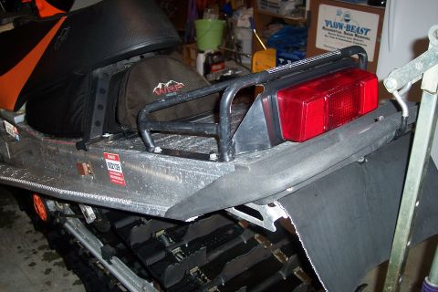 2004 Arctic Cat King Cat 900 - This snowmobile's rear section features a black seat, a storage bag, and a red taillight. A warning sticker is visible on the side.