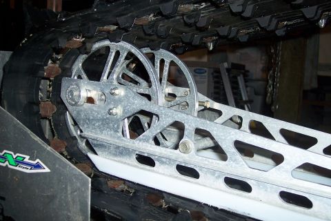 2004 Arctic Cat King Cat 900 - Close-up view of a snowmobile's track and suspension system, metallic components and a rubber track.