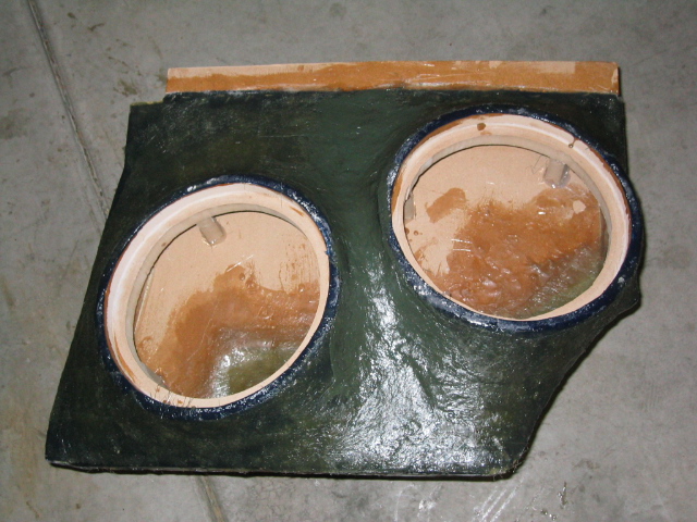 Homemade dark green fiberglass dual-subwoofer box baffle on a concrete floor