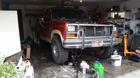1985 Ford Bronco - This 1985 Ford Bronco is parked in a garage with its hood removed, showing it is undergoing maintenance.