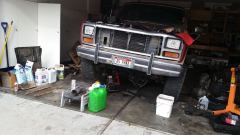 1985 Ford Bronco - A 1985 Ford Bronco is undergoing maintenance in a garage, with its front end elevated.