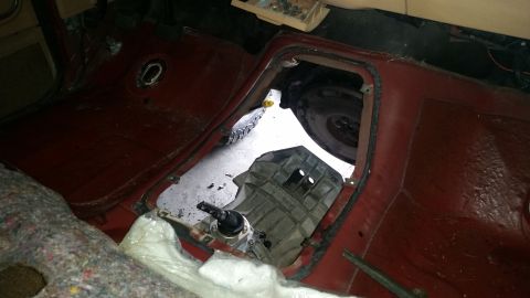 1985 Ford Bronco - The floor of a vehicle is shown with the transmission removed, revealing the driveshaft and surrounding components.