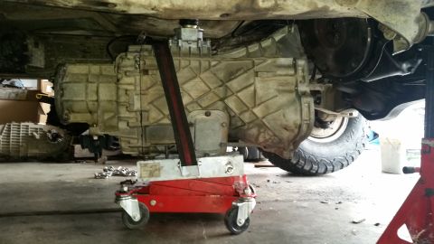 1985 Ford Bronco - A vehicle's transmission is supported by a jack during maintenance.