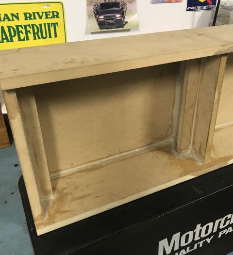 2014 Dodge 1500 - A custom-built wooden enclosure, possibly for audio equipment, sits on a black surface with a SuperMotors logo visible.