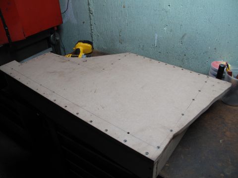 1994 Ford Bronco - A template for a subwoofer enclosure is prepared on a workbench, with tools visible in the background.