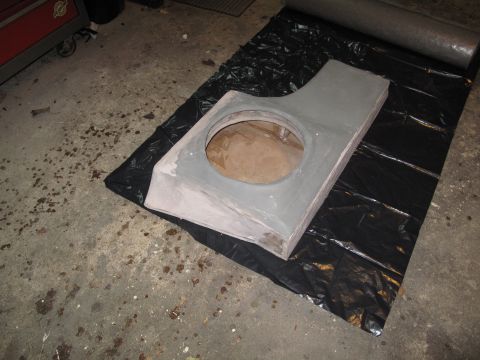 1994 Ford Bronco - A custom-built subwoofer enclosure, likely for a vehicle's interior, sits on black plastic sheeting on a concrete floor.