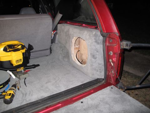1994 Ford Bronco - Installing a custom subwoofer enclosure in the rear cargo area of an SUV, with tools and a shop vac present.