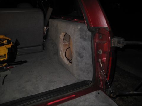 1994 Ford Bronco - Custom subwoofer box installed in the rear of a red SUV, with a power tool nearby.