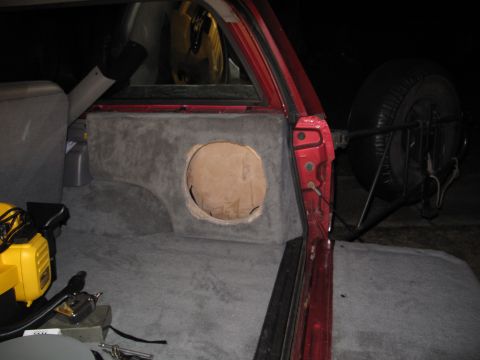 1994 Ford Bronco - The interior of a red SUV shows a custom subwoofer enclosure and a spare tire mount, with a yellow power tool visible.