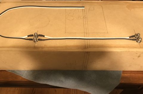 1995 Ford Bronco - A wiring harness with black and white wires and silver connectors is laid out on a wooden surface with drawn lines.