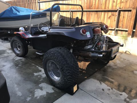 1970 Volkswagen Beetle - A custom dune buggy with a roll cage and exposed engine sits parked next to a boat on a trailer.