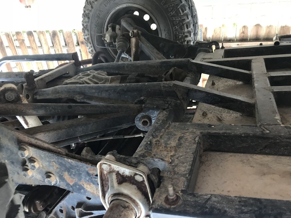 Underbody view of a vehicle showing frame, suspension components, and a tire