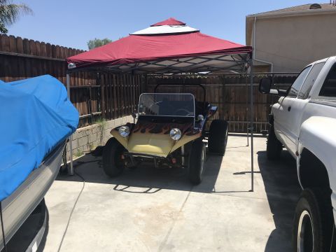 1970 Volkswagen Beetle - A custom dune buggy sits under a canopy, flanked by a pickup truck and a covered boat.
