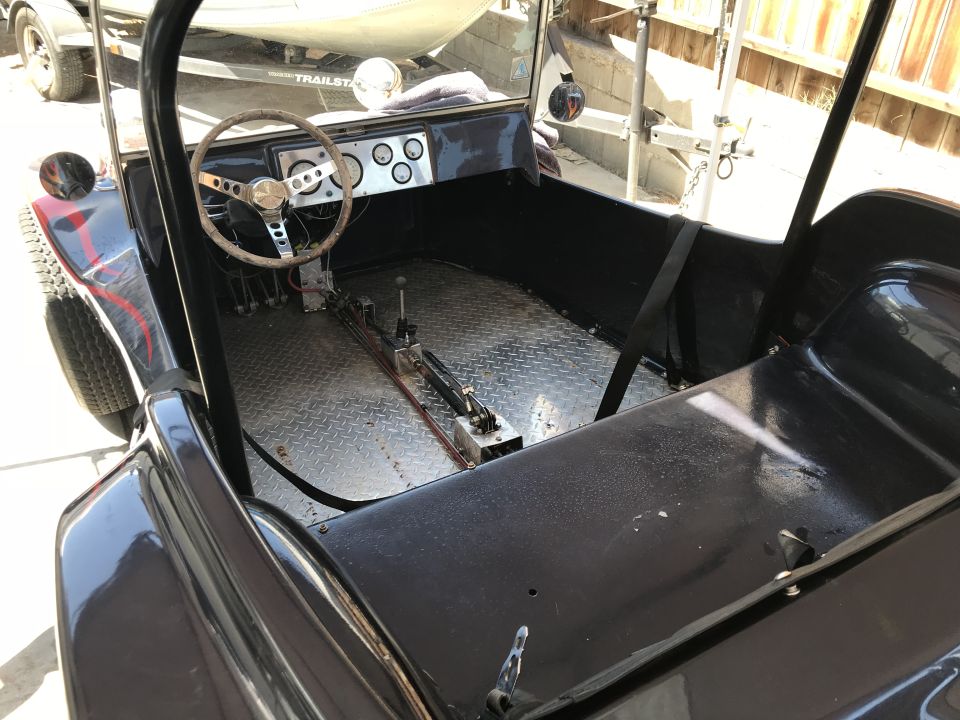 Dark grey custom dune buggy interior with diamond plate floor, aftermarket steering wheel, and three gauges