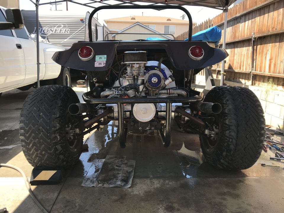 Rear view of a custom dune buggy with exposed engine and large tires. License plate visible