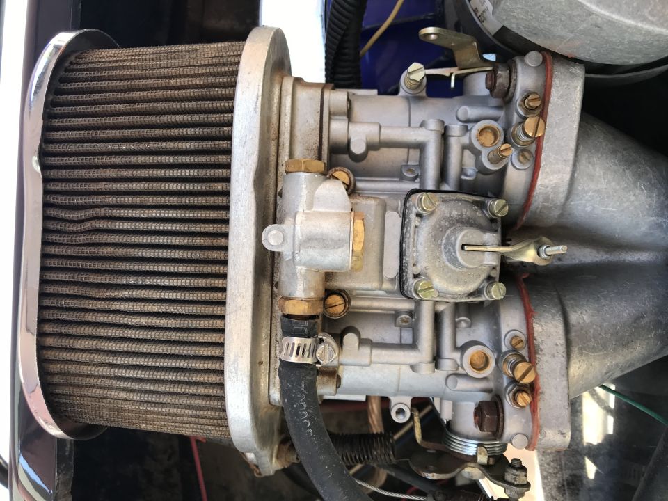 Close-up of a dual-throat carburetor and air filter on a vehicle.