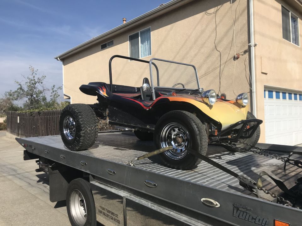 Black and yellow dune buggy with flame graphics on a tow truck.