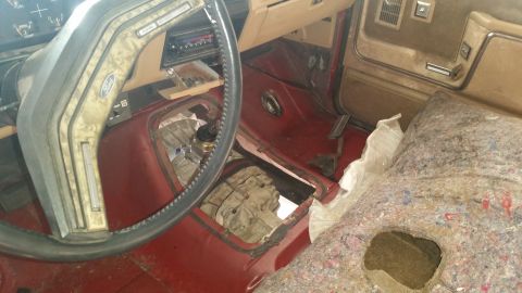 1985 Ford Bronco - Interior view of a Ford Bronco with the floor removed to expose the transmission and transfer case. The dashboard, steering wheel, and pass…