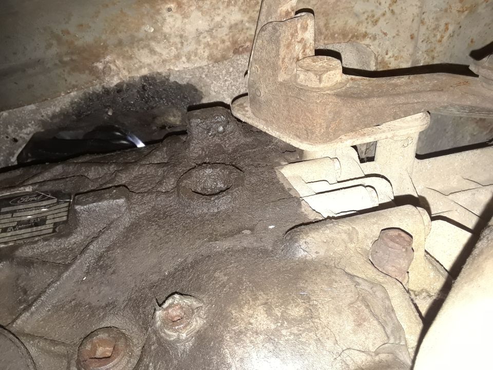 Underside of a dirty Ford F-350 transmission housing with a Ford identification tag.