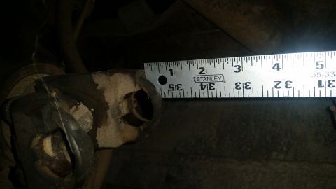 1985 Ford Bronco - A metal ruler is positioned next to a U-joint on a vehicle's drivetrain. The ruler's markings are visible, indicating measurements in inche…