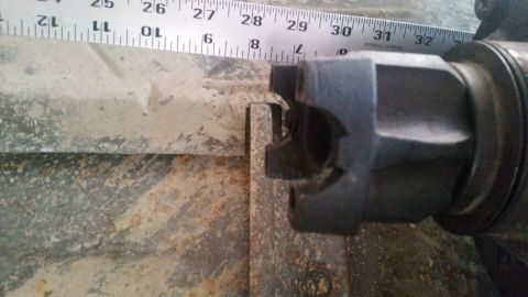1985 Ford Bronco - A close-up shot shows a metal measuring tape with inch and centimeter markings laid over a rusty metal surface. A dark-colored, multi-prong…