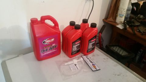1985 Ford Bronco - A red jug of Red Line D4 ATF and three red bottles of Motorcraft Transfer Case Fluid are displayed on a white surface, along with a fluid p…