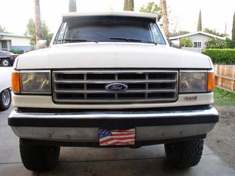 1988 Ford Bronco - This white Ford Bronco features a prominent chrome grille and 4x4 badging on the front fender.