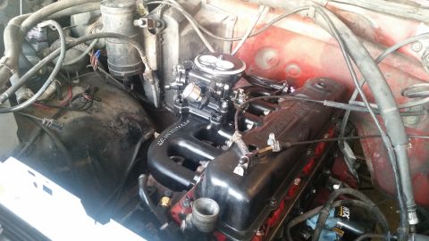 1985 Ford Bronco - Close-up view of a V8 engine with a black intake manifold and carburetor. The engine bay is cluttered with hoses, wires, and other componen…