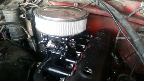 1985 Ford Bronco - A close-up view of a modified engine bay, featuring a black intake manifold, a chrome air cleaner assembly with a white filter, and various…